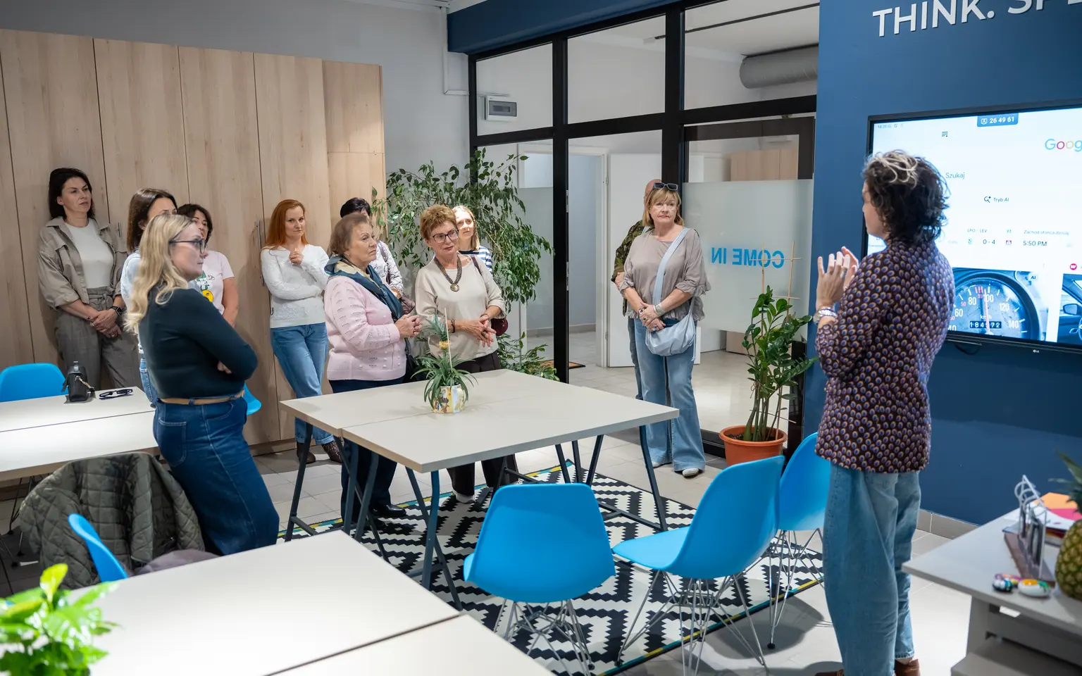 Learning Studio w Question House - 75-calowy monitor na granatowej ścianie i stoły dla uczestników treningu