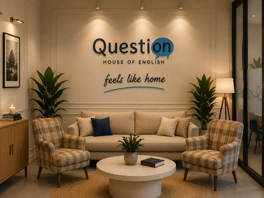 Strefa wejścia z sofą i dwoma fotelami, na ścianie logo Question House i hasło feels like home